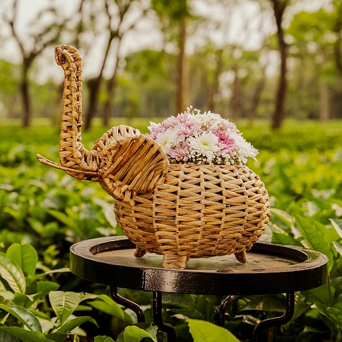 Close up picture of a cute elephant shaped wicker desktop planter with flowers in it