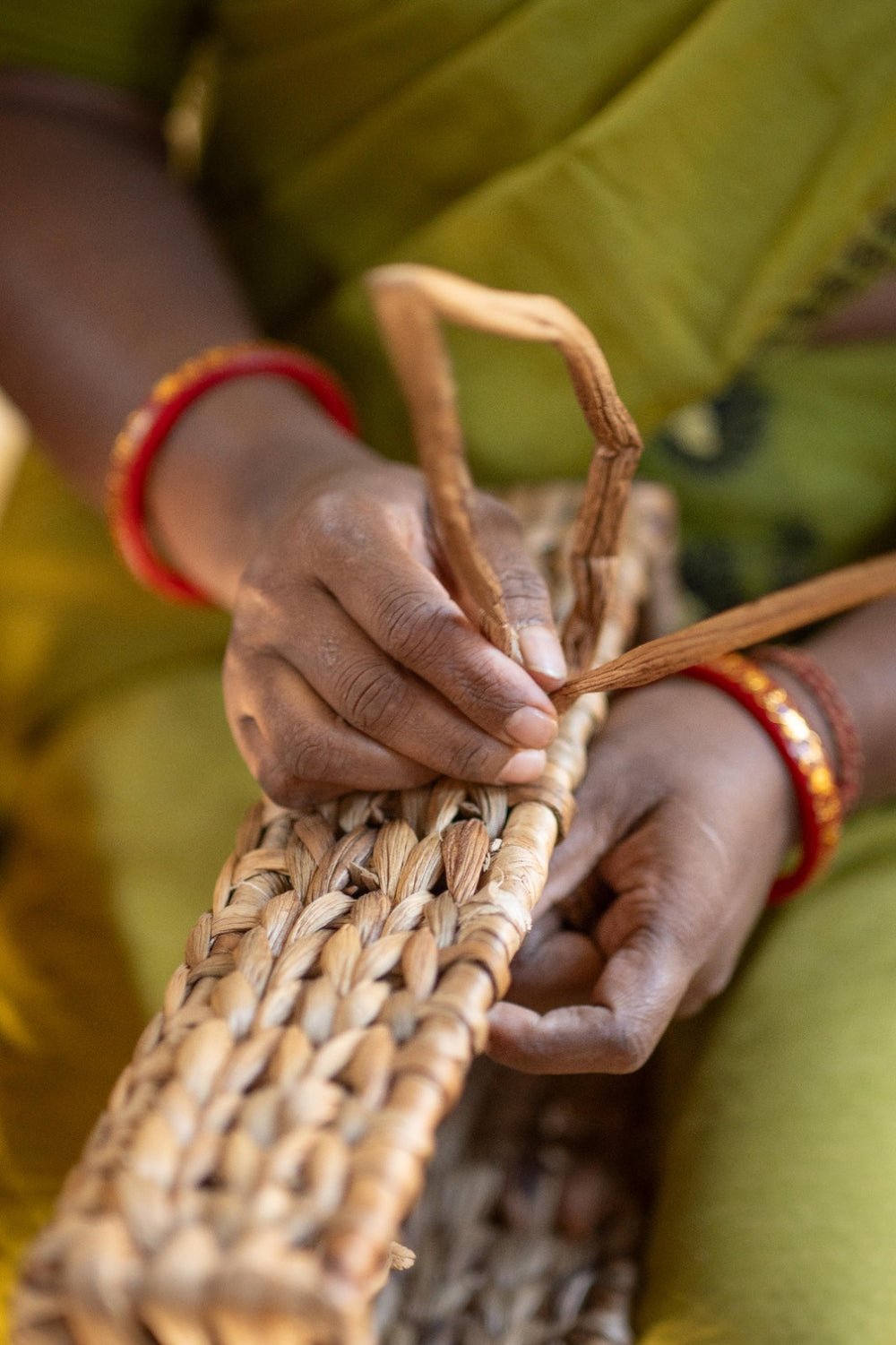 An Asama artisan braiding dried water hyacinth stems into a basket wall