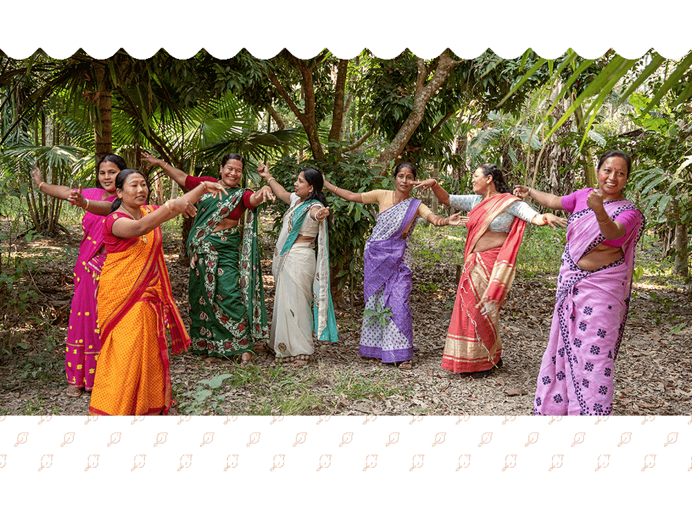 Women of Alimur village dancing together in bright saris under areca palms