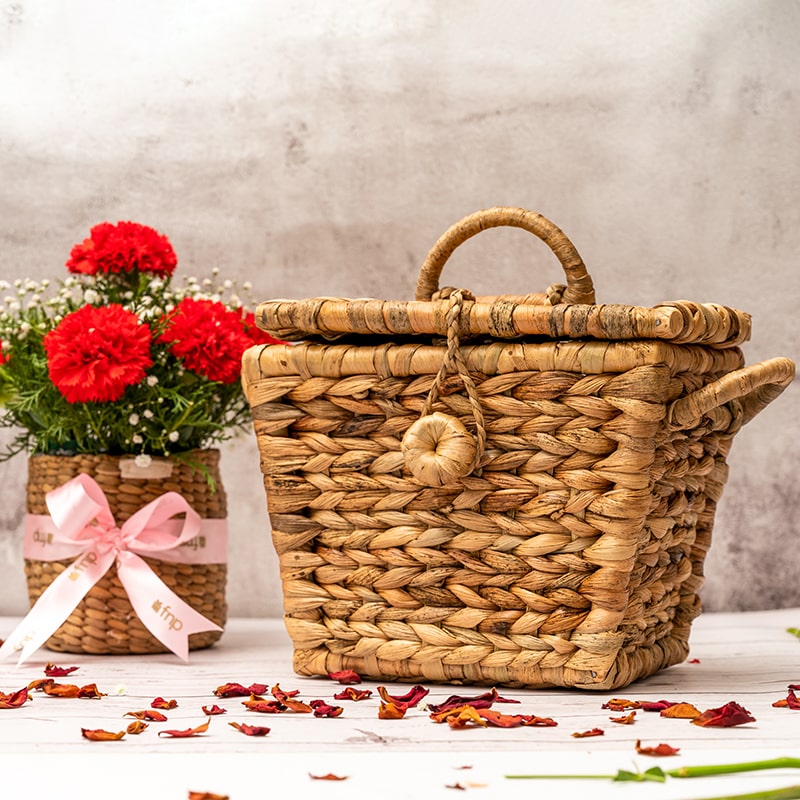 A close-up view of a handwoven wicker creel basket with a natural brown color and a classic design. The basket features a woven lid and a large opening for storing items. The wicker material is tightly woven, with a few gaps for ventilation, and the basket has a sturdy, structured shape. Two handles on either side allow for easy carrying. This wicker creel basket is a versatile and stylish storage solution for a variety of items, with a rustic and functional design