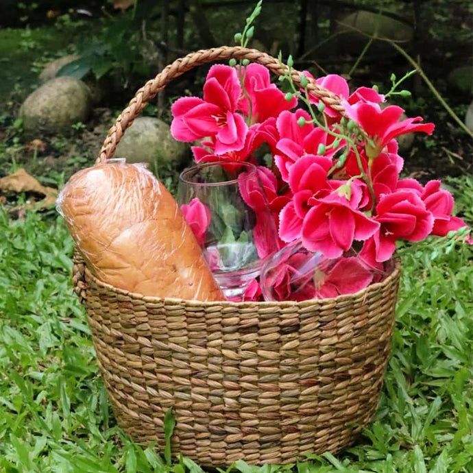 Image of a natural wicker tapered basket with a handle. This multipurpose basket is suitable for organizing, displaying or gifting. Its elegant design features a gradual taper and woven texture, making it a stylish addition to any home decor